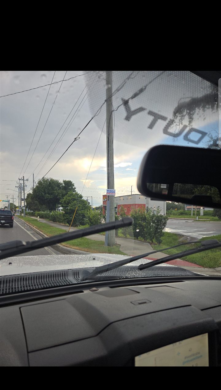 Full drive-by photo through a windshield; distant sign on a utility pole